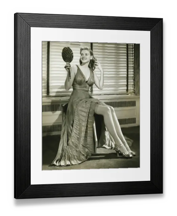 Framed Print : Young woman sitting on stool, holding mirror indoors, (B&W) Framed Print : Young woman sitting on stool, holding mirror indoors, (B&W)