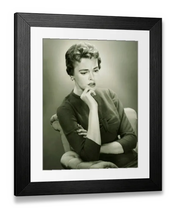 Framed Print : Distraught woman sitting in armchair in studio, (B&W), portrait Framed Print : Distraught woman sitting in armchair in studio, (B&W), portrait