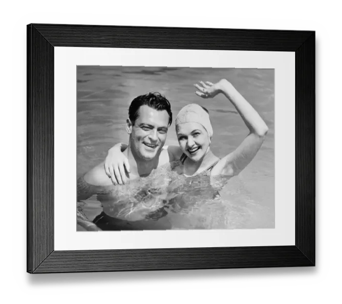 Framed Print : Young couple standing in pool, woman waving hand, (B&W), portrait Framed Print : Young couple standing in pool, woman waving hand, (B&W), portrait