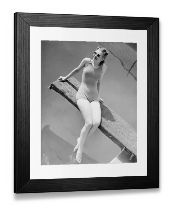 Framed Print : Young woman sitting on springboard, (B&W) Framed Print : Young woman sitting on springboard, (B&W)