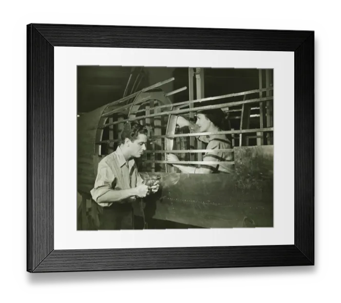 Framed Print : Young man and woman working in plane body in factory, (B&W) Framed Print : Young man and woman working in plane body in factory, (B&W)