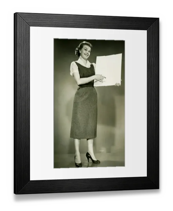 Framed Print : Woman holding blank sheet of paper, posing in studio, (B&W), portrait Framed Print : Woman holding blank sheet of paper, posing in studio, (B&W), portrait