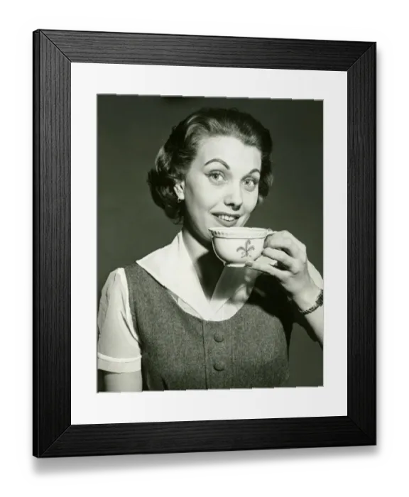 Framed Print : Smiling woman holding cup, posing in studio, (B&W), portrait Framed Print : Smiling woman holding cup, posing in studio, (B&W), portrait