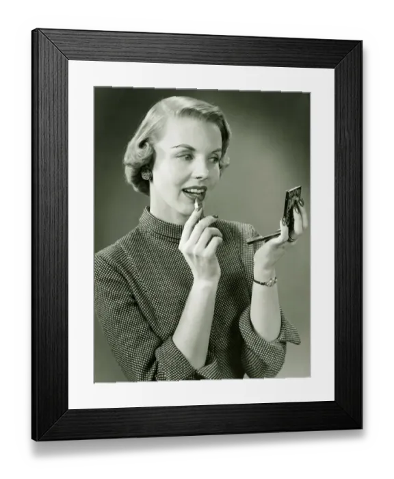Framed Print : Young woman applying lipstick, looking at powder compact mirror, (B&W), close-up Framed Print : Young woman applying lipstick, looking at powder compact mirror, (B&W), close-up