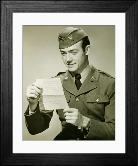 Framed Print : World War II Army solider reading letter in studio, (B&W), portrait Framed Print : World War II Army solider reading letter in studio, (B&W), portrait