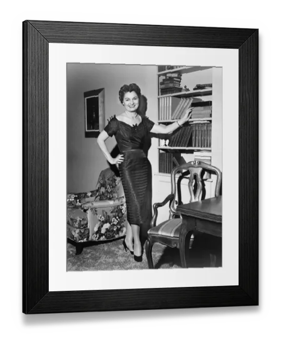 Framed Print : Woman standing in rich living room with hand on shelf, (B&W) Framed Print : Woman standing in rich living room with hand on shelf, (B&W)