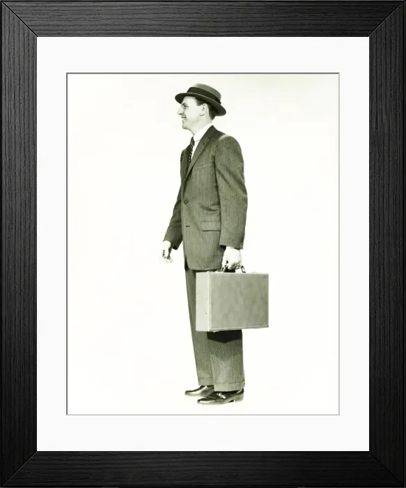 Framed Print : Businessman standing in studio, holding briefcase, (B&W) Framed Print : Businessman standing in studio, holding briefcase, (B&W)