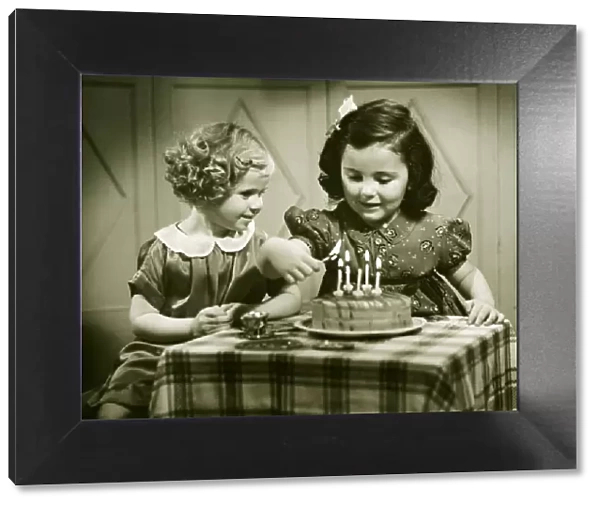 Two girls (3-4), (4-5) sitting at small table with birthday cake, (B&W)