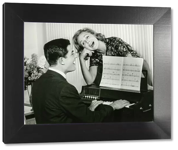 Young couple singing, man playing piano, (B&W)