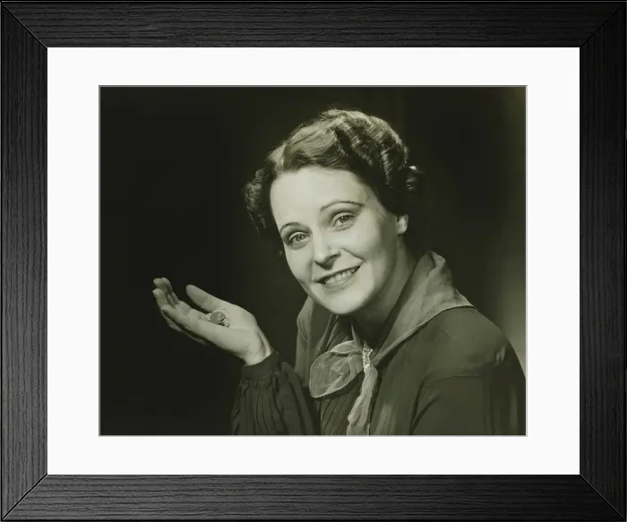Framed Print : Smiling woman holding coins, posing in studio, (B&W), close-up, portrait Framed Print : Smiling woman holding coins, posing in studio, (B&W), close-up, portrait