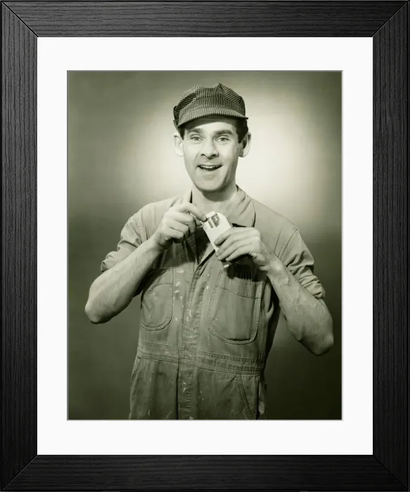 Framed Print : Young man in overalls showing card in studio, (B&W), portrait Framed Print : Young man in overalls showing card in studio, (B&W), portrait
