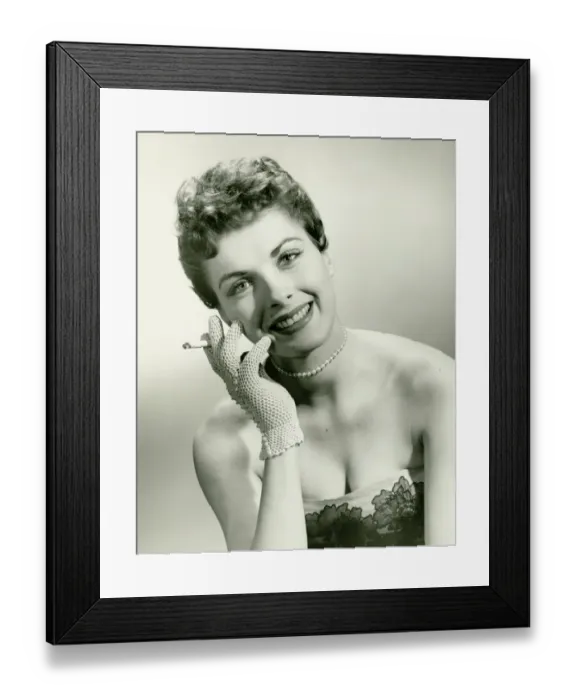 Framed Print : Woman wearing lace glove holding cigarette in studio, (B&W), portrait