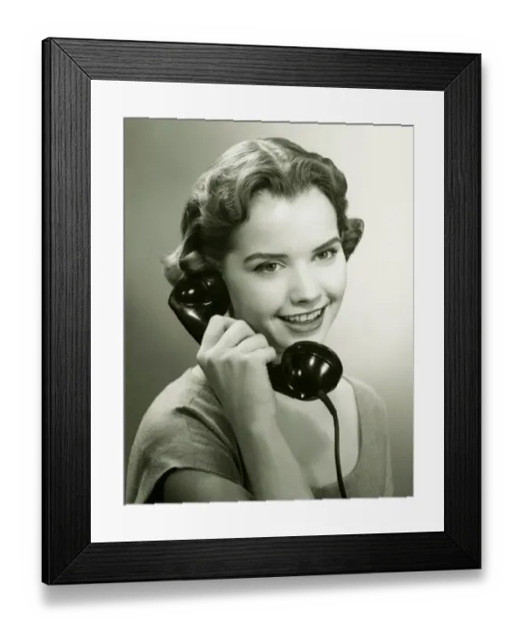 Framed Print : Young woman talking on phone in studio, (B&W), portrait Framed Print : Young woman talking on phone in studio, (B&W), portrait