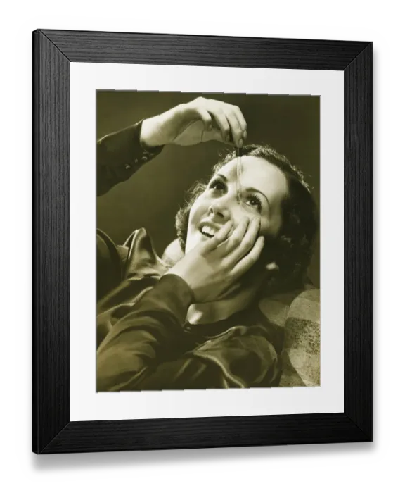 Framed Print : Woman using eye drop in studio, (B&W)