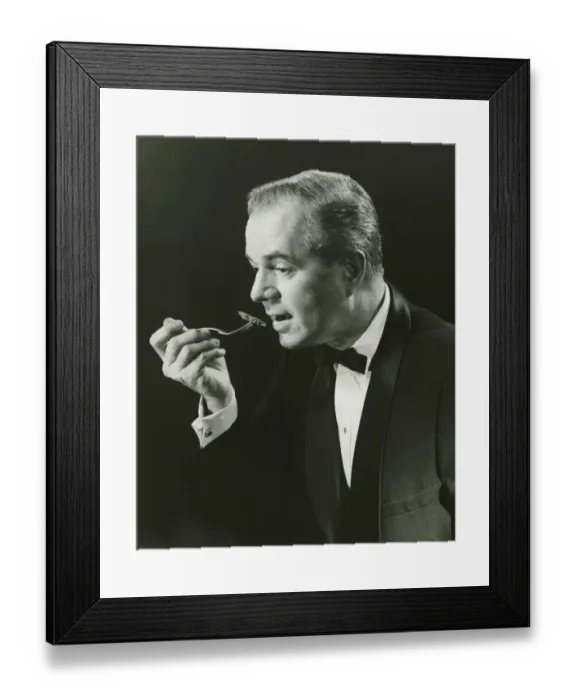 Framed Print : Man holding fork, taking bite in studio, (B&W), portrait Framed Print : Man holding fork, taking bite in studio, (B&W), portrait