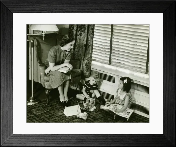 Framed Print : Mother watching over son and daughter (4-5) playing in living room, (B&W) Framed Print : Mother watching over son and daughter (4-5) playing in living room, (B&W)