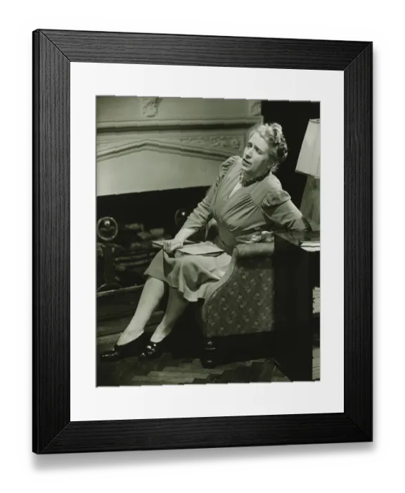 Framed Print : Woman suffering backache sitting on armchair by fireplace, (B&W)