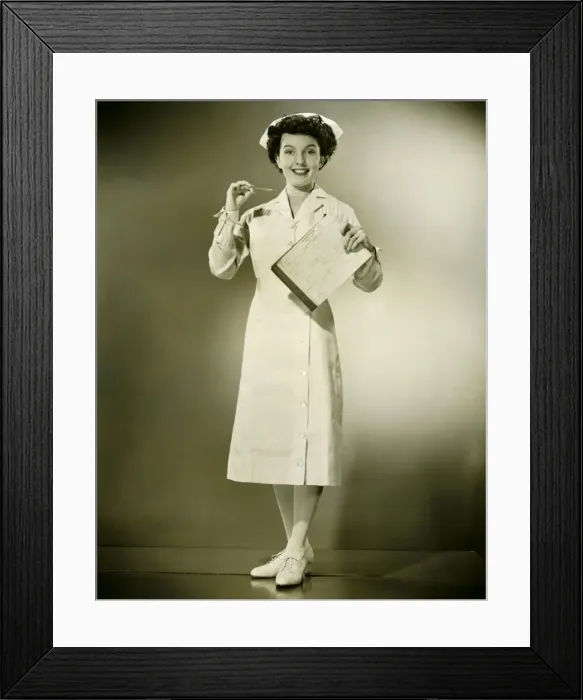 Framed Print : Smiling nurse holding thermometer and files in studio, (B&W), portrait Framed Print : Smiling nurse holding thermometer and files in studio, (B&W), portrait