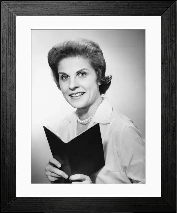 Framed Print : Woman holding notebook, smiling, (B&W), portrait Framed Print : Woman holding notebook, smiling, (B&W), portrait