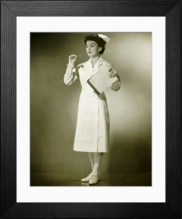 Framed Print : Smiling nurse holding thermometer and files in studio, (B&W), portrait Framed Print : Smiling nurse holding thermometer and files in studio, (B&W), portrait