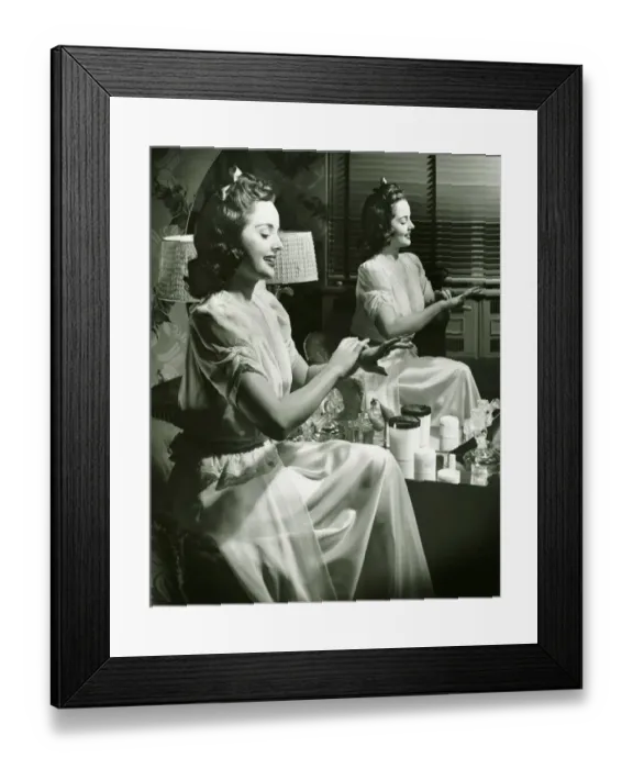 Framed Print : Young woman applying cream in front of mirror, (B&W) Framed Print : Young woman applying cream in front of mirror, (B&W)