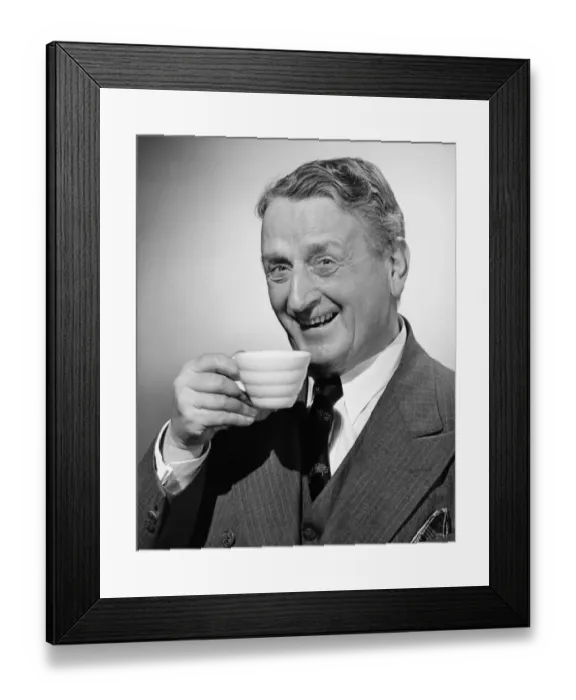 Framed Print : Senior man smiling with tea cup in hand, (B&W), portrait Framed Print : Senior man smiling with tea cup in hand, (B&W), portrait
