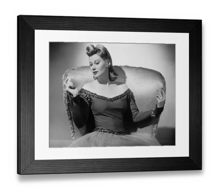 Framed Print : Woman in evening dress sitting in armchair, holding hands on backrest, (B&W) Framed Print : Woman in evening dress sitting in armchair, holding hands on backrest, (B&W)