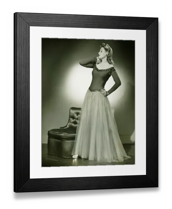 Framed Print : Woman in evening dress standing indoors, holding hand on cheek, (B&W) Framed Print : Woman in evening dress standing indoors, holding hand on cheek, (B&W)