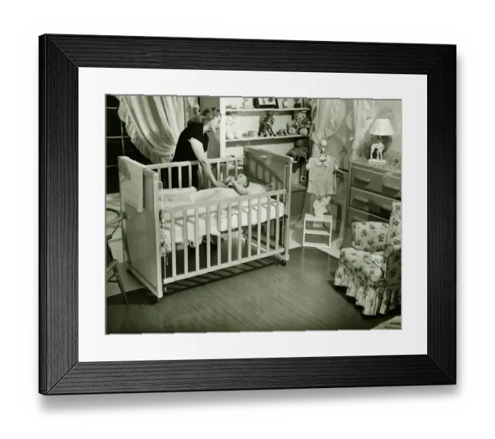 Framed Print : Mother looking at baby (3-6 months) lying in crib, (B&W) Framed Print : Mother looking at baby (3-6 months) lying in crib, (B&W)