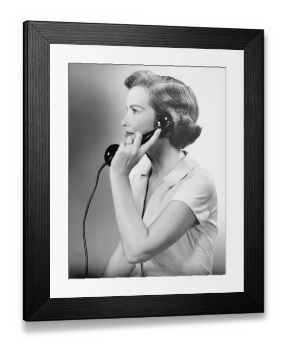 Framed Print : Young woman using phone, posing in studio, (B&W), close-up Framed Print : Young woman using phone, posing in studio, (B&W), close-up