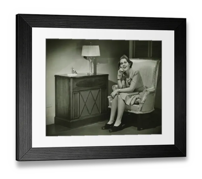 Framed Print : Woman sitting in armchair, smiling, (B&W) Framed Print : Woman sitting in armchair, smiling, (B&W)