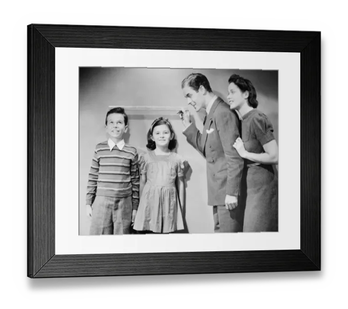 Framed Print : Parents measuring children standing against wall, boy (8-9) girl (6-7), (B&W) Framed Print : Parents measuring children standing against wall, boy (8-9) girl (6-7), (B&W)