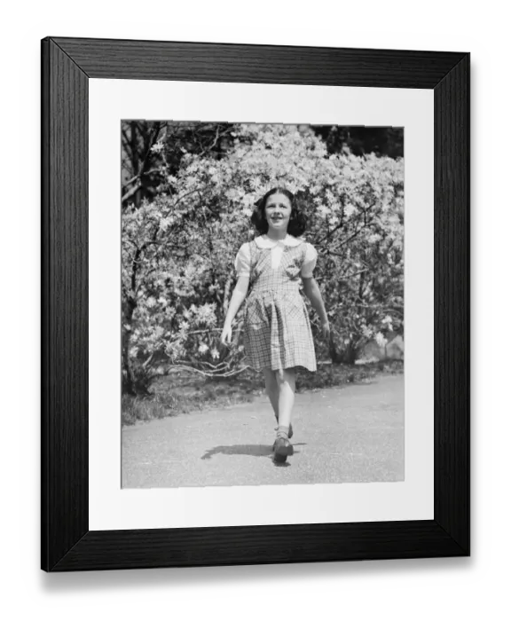 Framed Print : Young girl (8-9) walking on garden path, (B&W) Framed Print : Young girl (8-9) walking on garden path, (B&W)