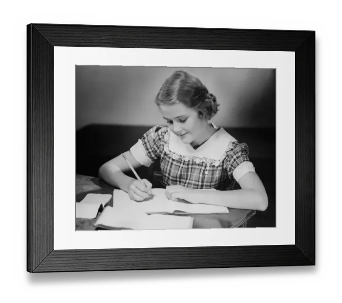 Framed Print : Young girl (12-13) at table doing schoolwork, (B&W) Framed Print : Young girl (12-13) at table doing schoolwork, (B&W)