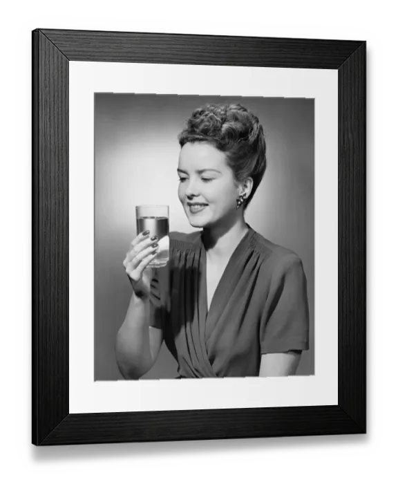 Framed Print : Elegant woman holding glass of water in studio, (B&W), portrait