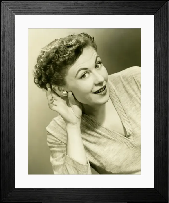 Framed Print : Woman cupping hand to ear in studio, (B&W), close-up, portrait Framed Print : Woman cupping hand to ear in studio, (B&W), close-up, portrait