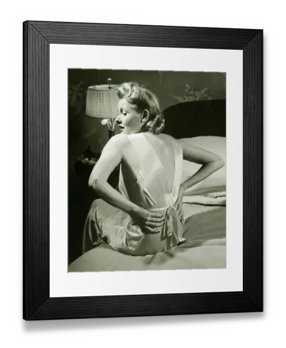 Framed Print : Woman suffering backache sitting on bed, (B&W)