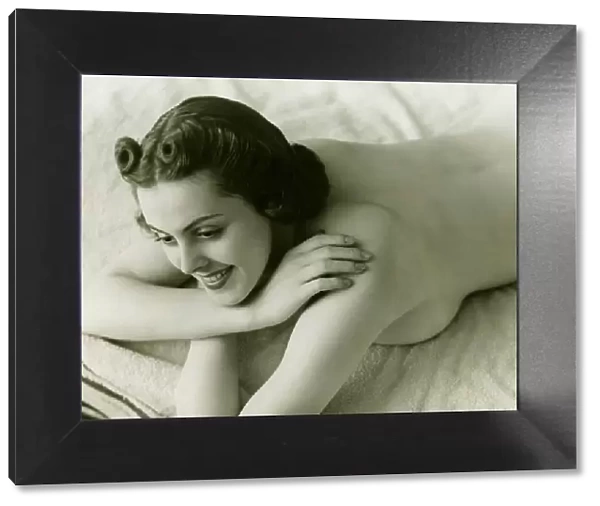 Nude woman lying face down on bed, (B&W)