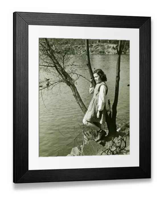 Framed Print : Girl (8-9) leaning on tree trunk by water, (B&W), elevated view Framed Print : Girl (8-9) leaning on tree trunk by water, (B&W), elevated view