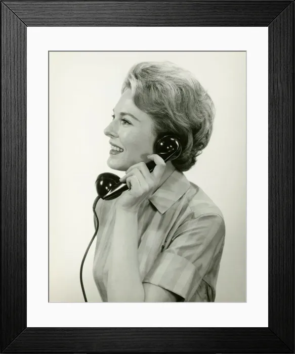 Framed Print : Woman using phone, posing in studio, (B&W), (Close-up) Framed Print : Woman using phone, posing in studio, (B&W), (Close-up)