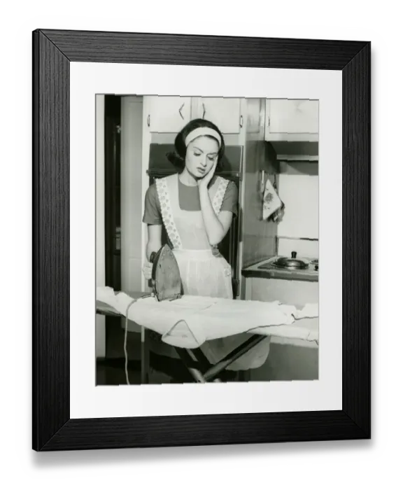Framed Print : Young woman ironing in kitchen, (B&W) Framed Print : Young woman ironing in kitchen, (B&W)