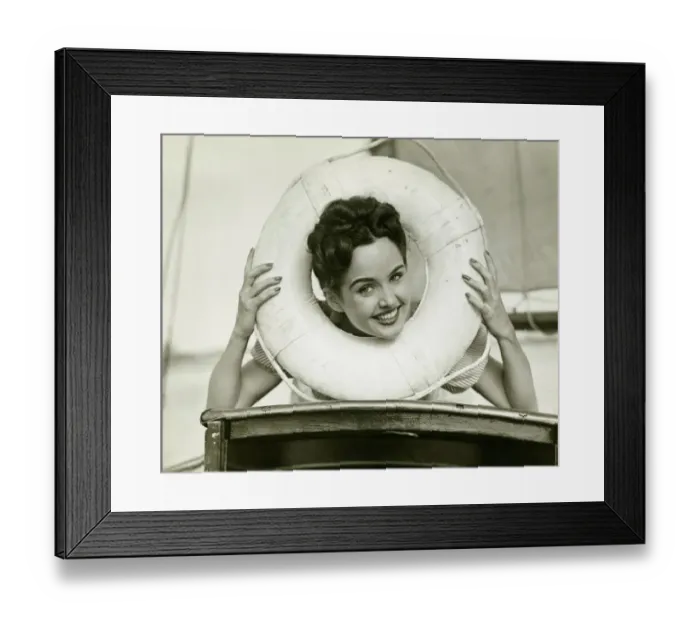 Framed Print : Young woman looking through lifebelt, smiling, (B&W)