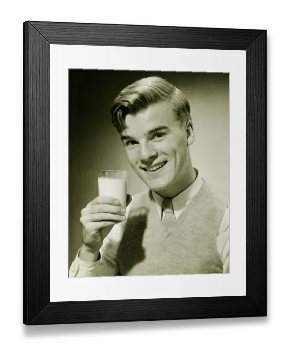 Framed Print : Young man holding glass of milk, smiling, (B&W), portrait Framed Print : Young man holding glass of milk, smiling, (B&W), portrait