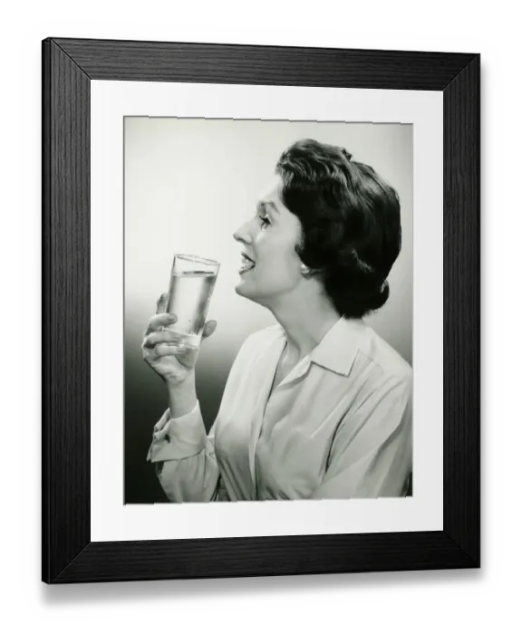 Framed Print : Woman holding glass of water, posing in studio, (B&W), (Portrait) Framed Print : Woman holding glass of water, posing in studio, (B&W), (Portrait)
