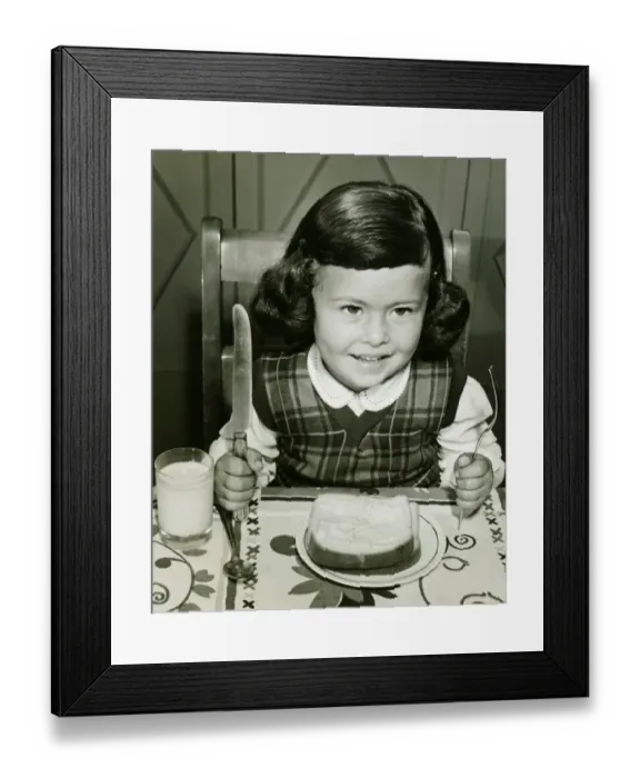 Framed Print : Girl (4-5) having meal, holding fork and knife, (B&W) Framed Print : Girl (4-5) having meal, holding fork and knife, (B&W)