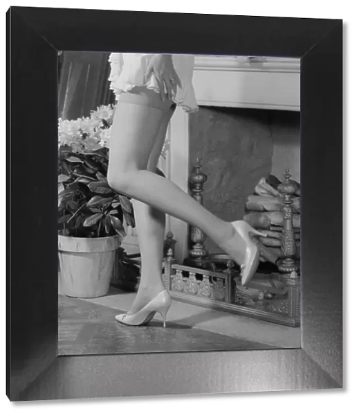 Woman in mini skirt and high heels dancing by fireplace, low section
