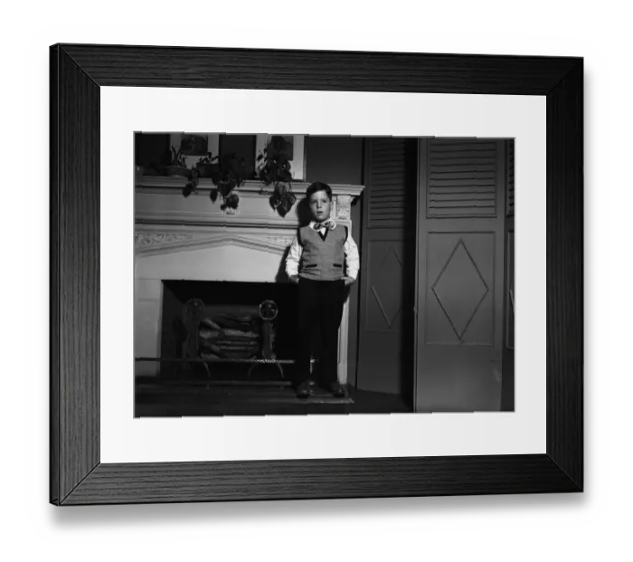 Framed Print : Boy (8-9) posing at fireplace, (B&W), portrait Framed Print : Boy (8-9) posing at fireplace, (B&W), portrait