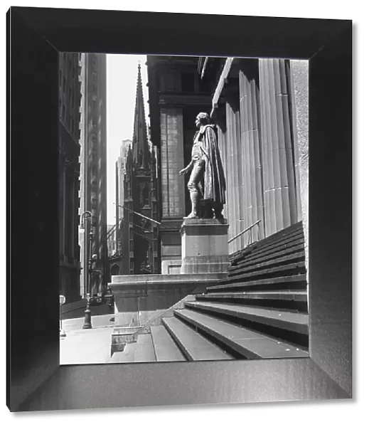 Statue at steps in front of building, Wall Street, Trinity Church in distance, New York City, USA (B&W)