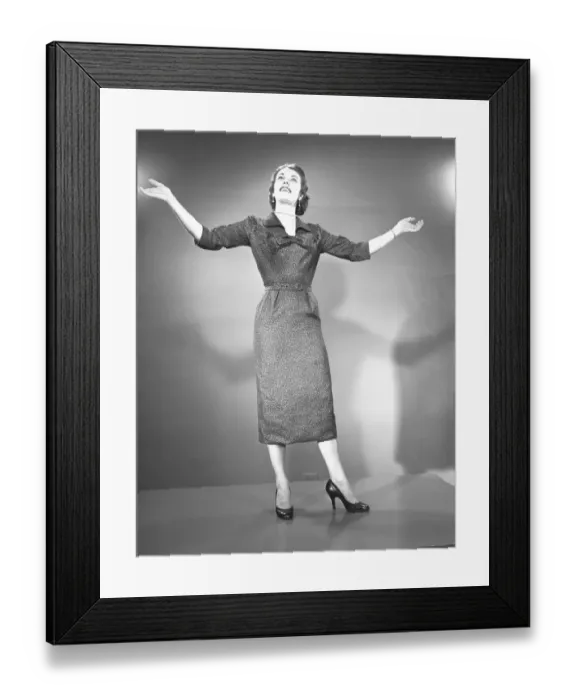 Framed Print : Woman raising hands in studio, (B&W)