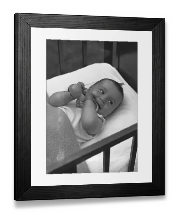 Framed Print : Baby (3-6 months) lying in crib, (B&W), elevated view